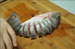 將鱸魚清洗干凈，從脊椎處切斷至腹部，腹部保留1cm左右不要切斷。