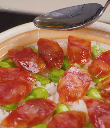 大米出現(xiàn)小孔時開蓋放香腸，往鍋邊淋入少許油，再燜煮8~10分鐘左右。