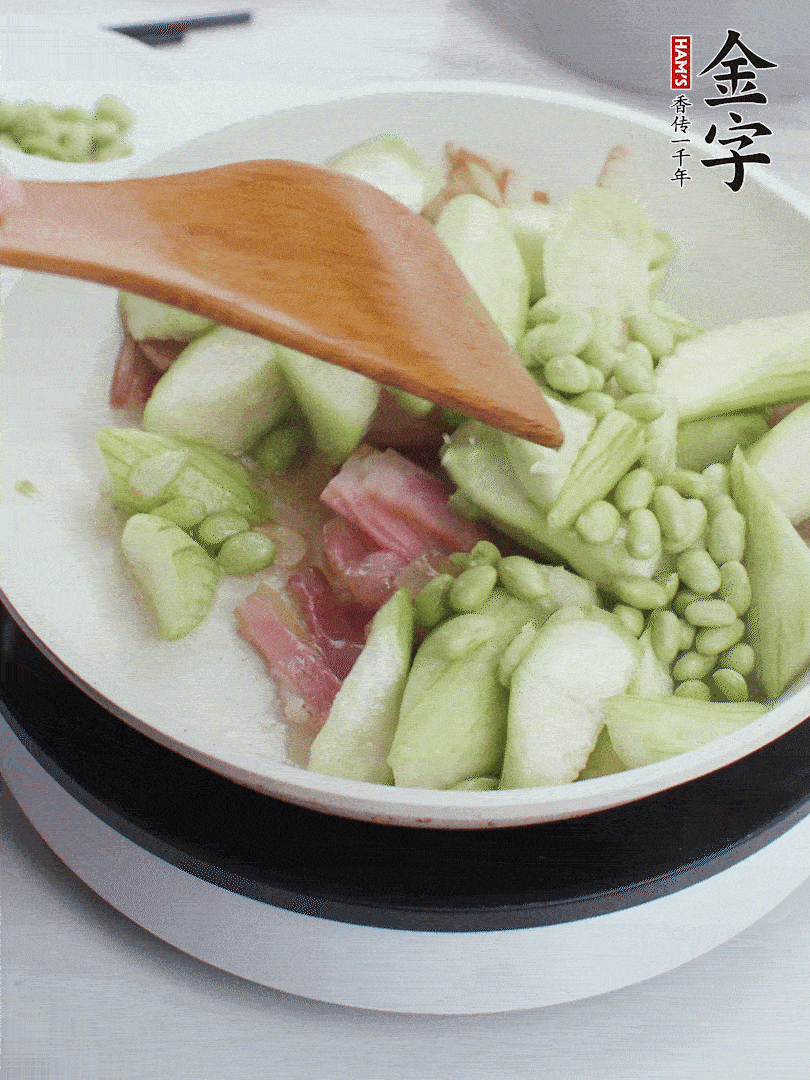 依次下絲瓜、青豆翻炒，炒至絲瓜打蔫縮小。