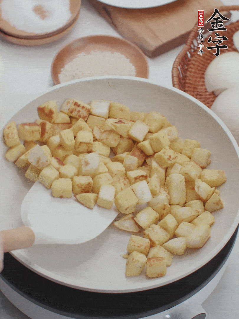 起鍋熱油，倒入饅頭丁，小火煎至蛋液凝固定型再翻面，饅頭丁部煎至金黃時(shí)盛起待用。