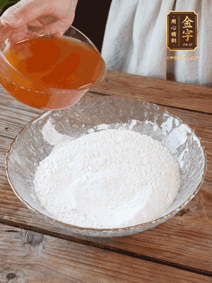 轉(zhuǎn)化糖漿、枧水、花生油攪拌均勻，加入面粉混合，醒發(fā)2小時(shí)。捏成23g一個(gè)的小球